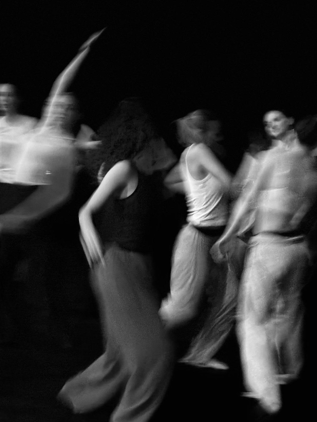 Black-and-white long-exposure photograph of women dancing together in community.
