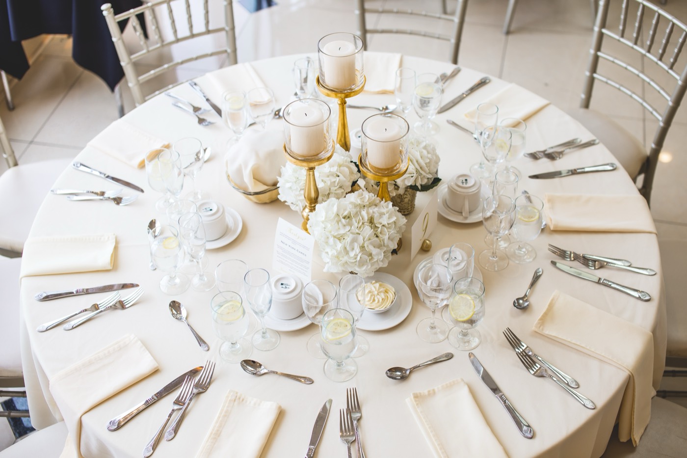 An elegant banquet table set with candles, white hydrangeas and polished glassware.