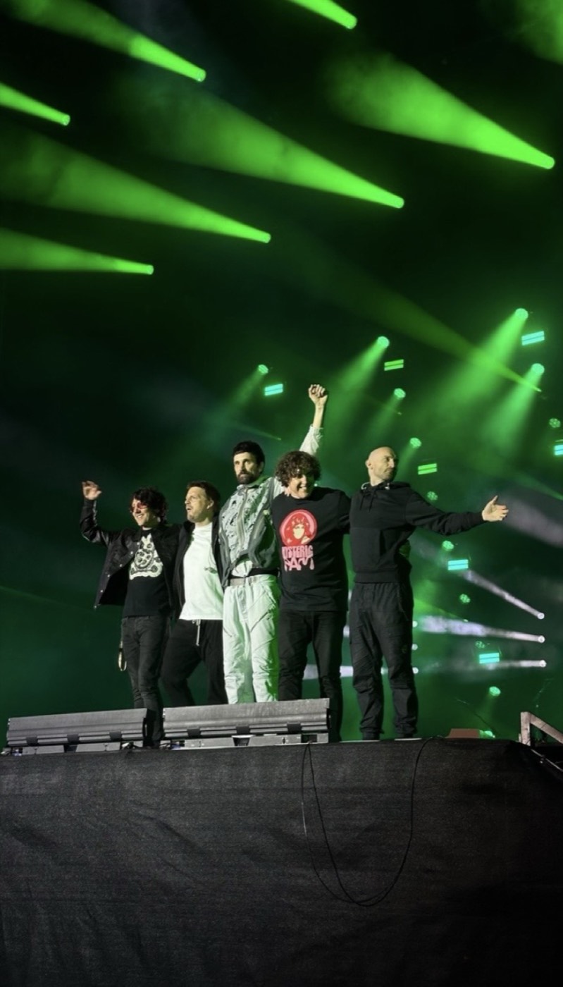 Kasabian on stage under green lighting at Summer Solstice II.