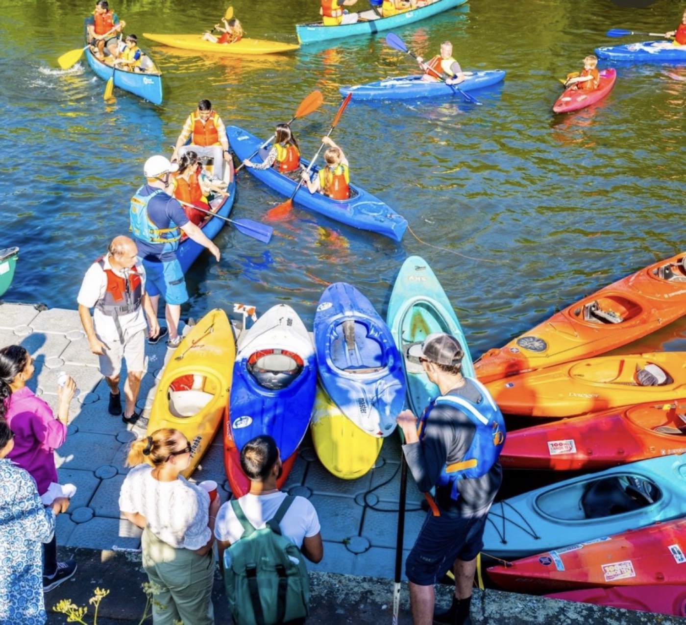 Colourful kayaks and canoes on the River Soar during the Riverside Festival, with families taking part in water activities.